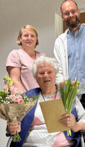 Gemeinsam mit Jean Borstel, stellvertretende Pflegedienstleiterin im Humanas-Wohnpark Tangermünde, (l.) hat Geschäftsführer Fabian Biastoch Bewohnerin Erna Tuscher im Wohnpark Tangermünde einen bunten Blumenstrauß zum 105. Geburtstag überreicht. Foto: Humanas
