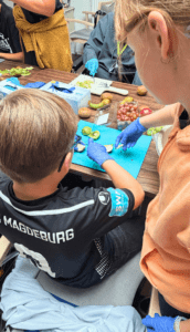Kinder der Villa Wertvoll haben gemeinsam mit Bewohnerinnen und Bewohnern im Wohnpark Heyrothsberge einen Obstsalat zubereitet. Foto: Humanas